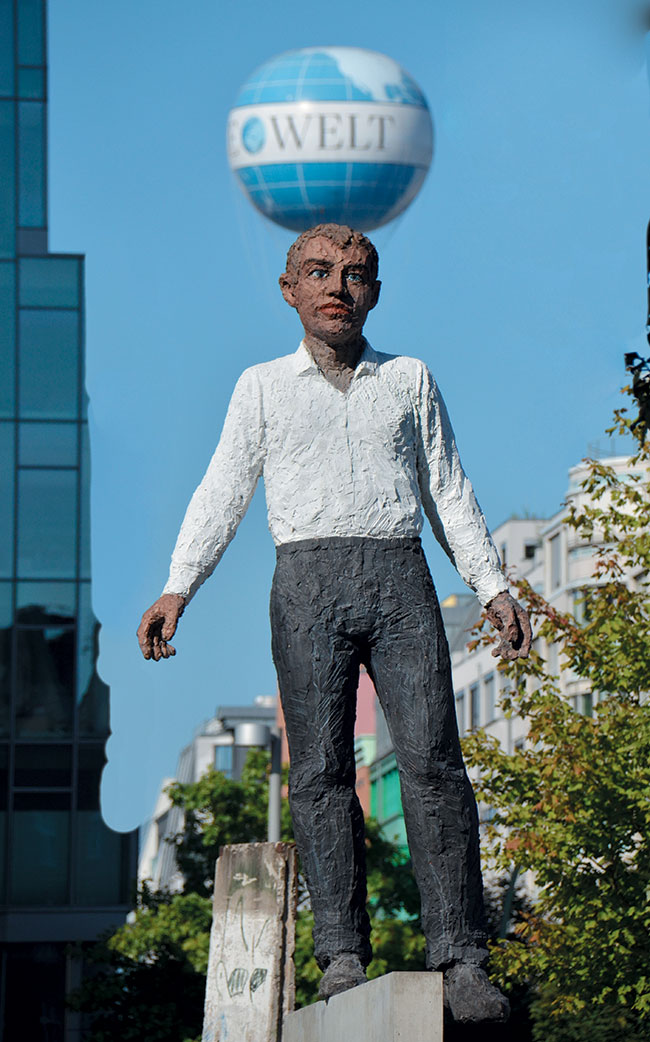 Rzeźba „Balancing Act” (autor Stephan Balkenhol) z 2009 roku. Wykonana na pamiątkę wkopania kamienia węgielnego pod siedzibą wydawnictwa Axel Springer (1959 r.) znajdującego się w Berlinie. W tle balon reklamowy Die Welt – dziennika wydawanego przez Axel Springer.