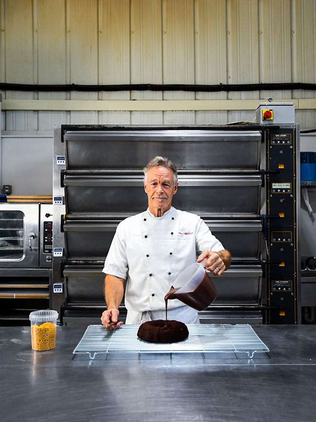 Mike Wallace, mistrz piekarnictwa, stoi przed ponad 100  ciastami boonarodzeniowymi Fot. Paloma Parrot: D7500, AF-S NIKKOR 50 mm f/1,4G
