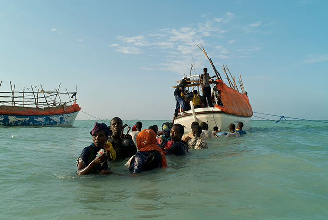 SHIMBIRO, SOMALIA- NOVEMBER 2007 Standing in choppy shoulder deep water, Somali refugees look back anxiously from the sea as they try to locate friends and relatives left behind on Shimbiro Beach. Preparing to board one of three smuggler’s boats that will depart simultaneously for Yemen, many of the passengers have become separated from those that they had hoped to make this high-risk journey with.As the crew hauls passengers from the water, each is already soaking wet as they step onboard. Before they even depart, the one hundred and twenty eight Somalis and Ethiopians tied down inside the tiny boat begin to shiver as strong winds blow in for the sea. Their fate is now sealed. Only eleven of the people who took this boat were to ever reach Yemen alive.