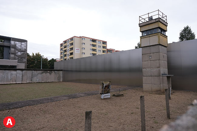 Okolice muzeum muru berliskiego. W takich sytuacjach przydaje si odchylany ekran. Wie stranicz mona dopiero uwieczni [A} po wystawieniu aparatu nad mur i kontroli ekspozycji za spraw odchylanego ekranu. Bez tego rozwizania moemy jedynie sfotografowa przez szpar w murze skrzynk elektryczn [B].