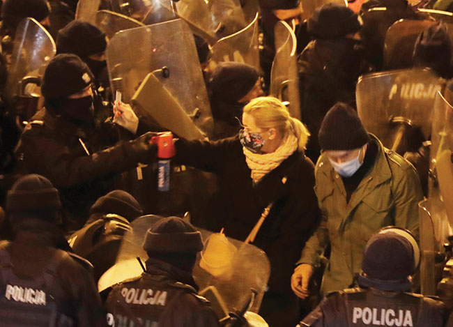 Podczas pokojowej manifestacji kobiet w 102 rocznice uzyskania praw wyborczych posanka Barbara Nowacka pokazuje legitymacj poselsk policjantowi, który atakuje j gazem pieprzowym. 28 listopada 2020 r., Warszawa, (fot. AP Photo/Czarek Sokoowski).
