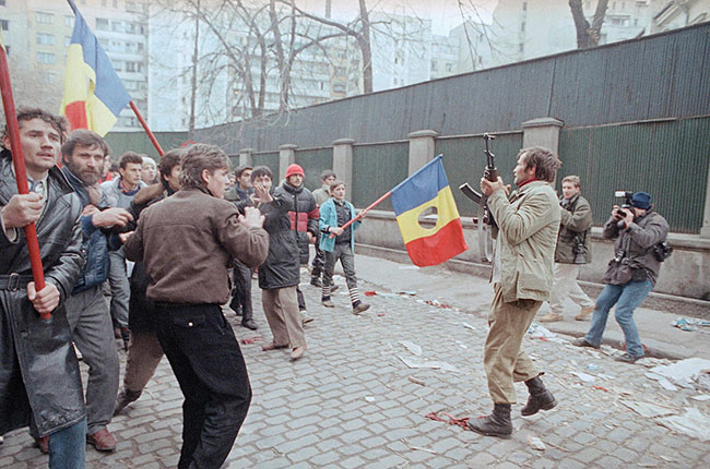 Wojskowy w cywilnym ubraniu wystrzeliwuje w powietrze, 27 grudnia 1989 r., aby powstrzyma szalestwo antykomunistycznych demonstrantów. Demonstranci wanie wysuchali przemówienia na ulicy, mówicego, e Rumunia bdzie miaa now form komunizmu, które wywoao demonstracj z okrzykami „Nie ma komunizmu”. (fot. AP Photo / Czarek Sokoowski)