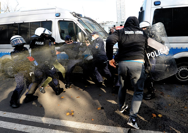 Polska policja celuje pojemniki z gazem zawicym w protestujcych rozgniewanych nowymi ograniczeniami majcymi na celu zwalczanie pandemii koronawirusa w Warszawie, w sobot 24 padziernika 2020 r. Wród protestujcych byli przedsibiorcy, skrajnie prawicowi politycy, kibice i przeciwnicy szczepionek. Protestujcy, wielu bez masek ochronnych, zamali nowe ograniczenie dotyczce gromadzenia si wikszej liczby osób. (fot. AP Photo / Czarek Sokoowski)