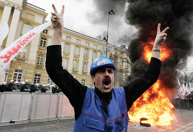 Polscy stoczniowcy pal opony i wykrzykuj hasa, domagajc si od rzdu ochrony ich miejsc pracy, Warszawa, wtorek 15 grudnia 2009 r. Tysice pracowników zwizku zawodowego Solidarno maszerowao w stolicy Polski, domagajc si od rzdu ochrony miejsc pracy w przemyle. Robotnicy zebrali si we wtorek przed gabinetem premiera Donalda Tuska w centrum Warszawy, niosc biao-czerwone flagi zwizku zawodowego Solidarno, dmuchajc w rogi i podpalajc stos opon. (fot. AP Photo / Czarek Sokoowski)