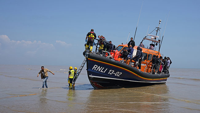 A group of people thought to be migrants crossing from France come ashore from the local lifeboat at Dungeness in Kent, after being picked up following a small boat incident in the Channel. Picture date: Tuesday July 20, 2021.  Photograph: Gareth Fuller