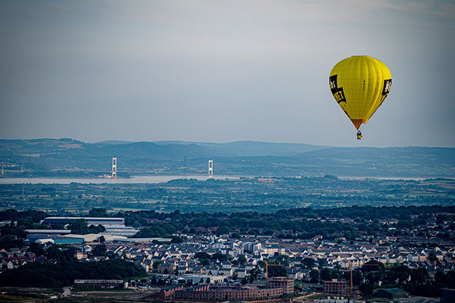 The Prince of Wales bridge, over the Severn Estuary is seen as balloons float above Filton, North Bristol, during the first mass ascent during 'Fiesta Fortnight' that will see hundreds of balloons above the skies of Bristol over two weeks, culminating in the Bristol International Balloon Fiesta at Ashton Court Estate. Picture date: Wednesday August 4, 2021.  Photograph: Ben Birchall