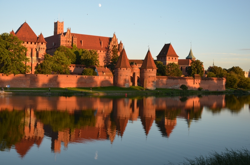 Zamek w Malborku, odbicie lustrzane w rzece Nogat przy zachodzie soca